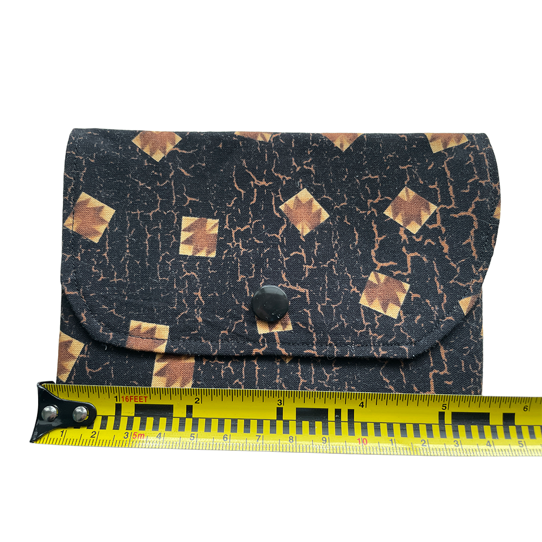 Fabric pouch with geometric pattern next to a measuring tape on a white background