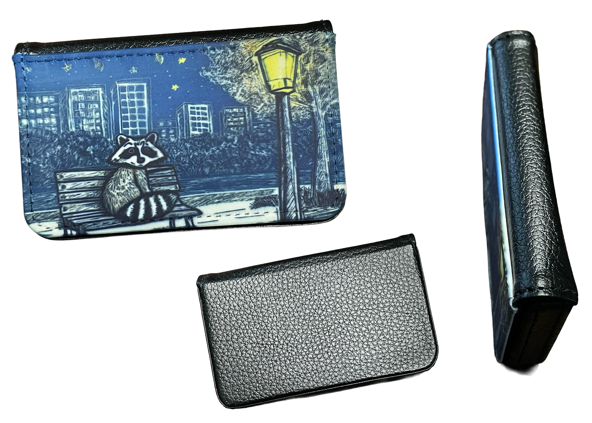 Small card holder with raccoon design, folded cardholder, and black leather wallet on a white background