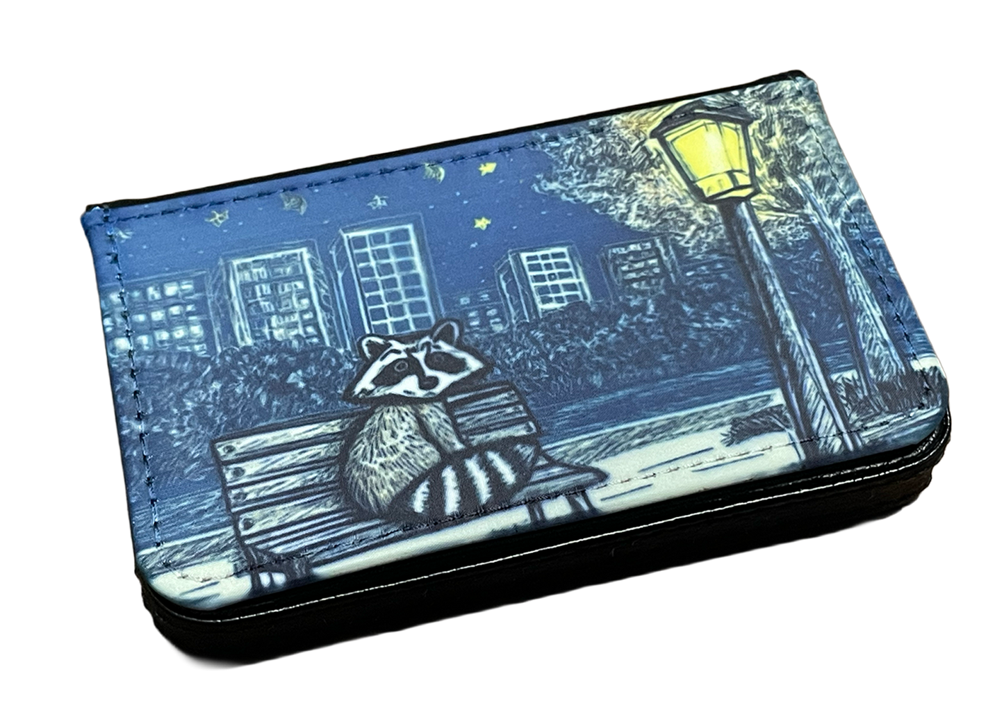 Wallet with raccoon design on a bench under a street lamp at night.