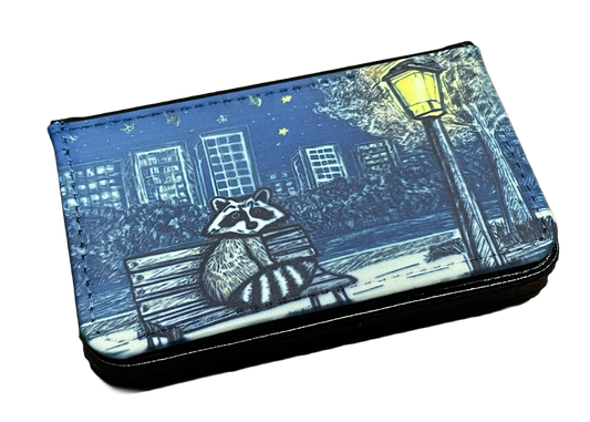 Wallet with raccoon design on a bench under a street lamp at night.