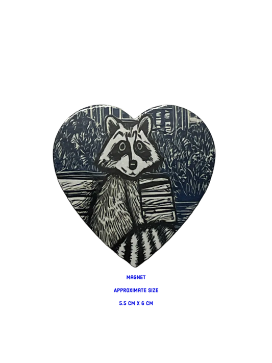 Heart-shaped magnet with a raccoon design on a bench 5.5 cm x 6 cm
